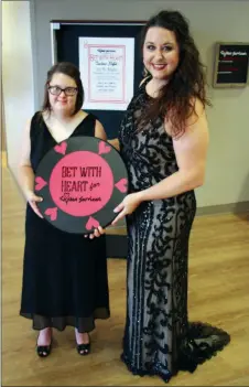  ?? SAM PIERCE/TRILAKES EDITION ?? Lyndsey Smith, left, and Bekka Wilkerson, special events coordinato­r for Civitan Services, pose with a giant poker chip inside the offices for the adult-service campus in Bryant. Civitan Services will host the first Bet With Heart Casino Night on July 26.
