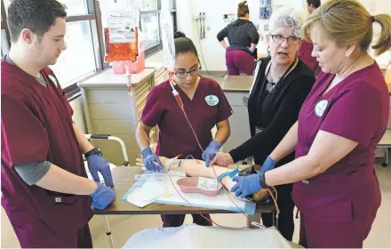  ?? CLYDE MUELLER/THE NEW MEXICAN ?? Nursing student Jenny Vigil, right, gets advice from Pat Shindler, adjunct nursing faculty instructor, on the correct way to administer an IV while Margarita Baldonado, center, and Brandon Esparsen listen April 5 during a skills lab at Santa Fe...