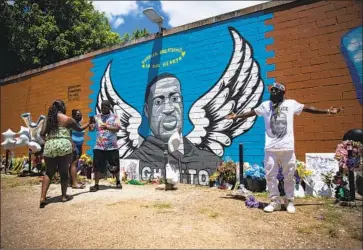  ?? Annie Mulligan ?? OG BEZEL, right, joins other visitors to the mural honoring George Floyd in Houston’s Third Ward, where Floyd grew up. Friends, former classmates and teammates prepared for his third and final funeral Tuesday.