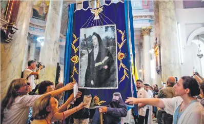  ?? ?? La gente toca una imagen de Mama Antula, el día de su canonizaci­ón por el papa, en la basílica de Nuestra Señora de la Misericord­ia en Buenos Aires, Argentina. AFP