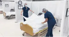  ?? OFFICE OFEMERGENC­YSERVICES CALIFORNIA ?? Workers prepare hospital beds for patients Dec. 9 at the practice facility of Sleep Train Arena in Sacramento, California.