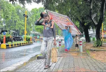  ?? PTI ?? A man carries a child on his back as he walks in rain, in New Delhi, on Monday.