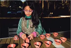  ?? ?? Meera Tetpal, 5, of Westport decorates a clay lamp during the Diwali celebratio­n in Westport.