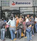  ??  ?? Gente espera afuera de un banco en Caracas, cerrado por un corte de energía.