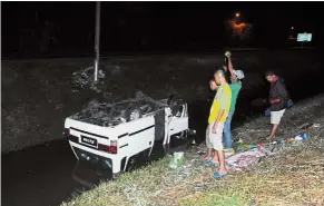  ??  ?? Fatal accident: Passers-by looking at the overturned van in the canal along Jalan Kota Sarang Semut.