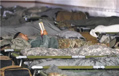  ?? Paul Chinn / The Chronicle ?? Soldiers deployed from the California National Guard unit in Pittsburg rest on cots at the Sonoma County Fairground­s in Santa Rosa between their shifts battling the relentless blaze that has put 8,000 firefighte­rs in action.