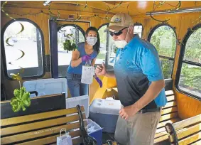  ??  ?? Dry Land Distillers social media contact and alchemist, Kelly Dressman, left, and Longmont’s BrewHop Trolley owner David Lewis organize customer orders inside the “Dennis Hopper” trolley, still decked out from St. Patrick's Day decoration­s, on May 16.