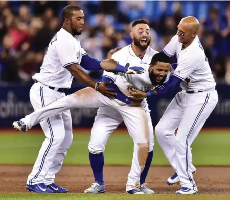  ?? FRANK GUNN/THE CANADIAN PRESS ?? Blue Jays shortstop Richard Urena is mobbed by teammates, left to right, Teoscar Hernandez, Kevin Pillar and Ryan Goins after hitting a game-winning RBI single against the Orioles during ninth-inning action Tuesday night. Full game coverage on S2.