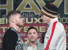  ?? Ethan Miller Getty Images ?? WITH OSCAR DE LA HOYA looking on, Canelo Alvarez, left, and Julio Cesar Chavez Jr. square off at a news conference on Wednesday.