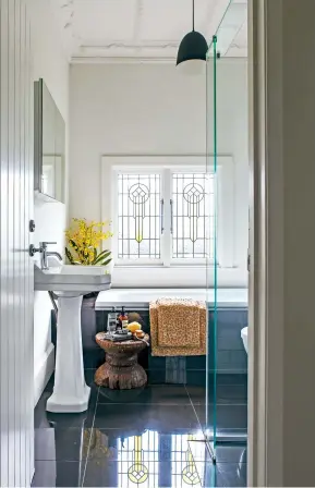  ??  ?? THIS PAGE (from left) Soft amber light from the leadlight windows creates a restful bathing space: “I love to have a soak in a nice bath oil,” Jo says. Hinkley lights, moved from the lounge, give drama to the back hall, where a sisal runner adds earthy texture.