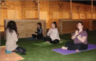  ??  ?? Women participat­ing in a victress-themed yoga focus on their breathing. The group tried axe throwing for the first time after the yoga session.