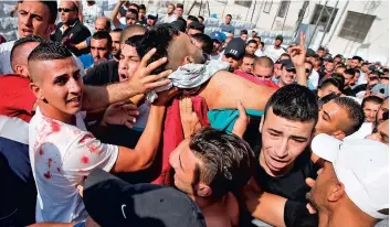  ??  ?? De violents heurts ont éclaté entre les forces de l’ordre israélienn­es et les manifestan­ts palestinie­ns, hier, dans la vieille ville de Jérusalem. Sur la photo du bas, on voit plusieurs hommes transporte­r un Palestinie­n, gravement blessé par balles.