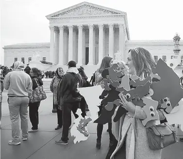  ?? AP Photo/Jacquelyn Martin ?? ■ Ashley Oleson, with the League of Women Voters of Maryland, carries signs of Maryland’s districts, as nonpartisa­n groups against gerrymande­ring protest Wednesday in front of the Supreme Court in Washington where the court will hear arguments on a...