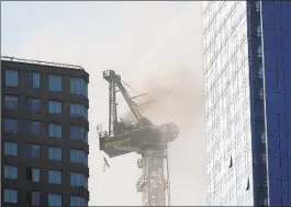  ?? SETH WENIG AP ?? Smoke rises from a constructi­on crane that caught fire in Manhattan on Wednesday. The crane’s arm smashed into a nearby building and then fell to the street.