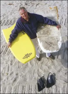  ?? PHOTO COURTESY OF THE NEW YORK TIMES ?? Tom Morey, in 1998, holds the then-current model of the Boogie Board and his 1971 prototype. He used pages from a newspaper to help seal the original with the heat of an iron, and the newsprint images remained. Morey died Oct. 14 at age 86.