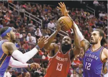  ?? Michael Wyke / Associated Press ?? Rockets guard James Harden works for a tough basket against the Carmelo Anthony (left) and Steven Adams this month.