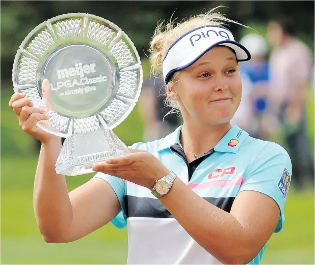  ?? CORY OLSEN / THE GRAND RAPIDS PRESS VIA AP ?? Canada’s Brooke Henderson is all smiles as she poses with the trophy after winning the Meijer LPGA Classic golf tournament at Blythefiel­d Country Club on Sunday in Grand Rapids, Mich. The Smiths Falls, Ont., teen shot a 66 in the final round to finish...