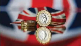  ?? — AFP ?? A stack of one pound sterling coins sit in front of a British Union flag in this photograph in London.