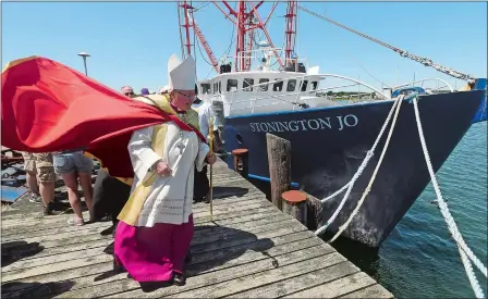  ?? DANA JENSEN/THE DAY ?? The Most Rev. Michael Cote, bishop of the Diocese of Norwich, walks to the next fishing vessel Sunday while blessing the boats at the Stonington Town Dock during the Blessing of the Fleet in Stonington Borough.