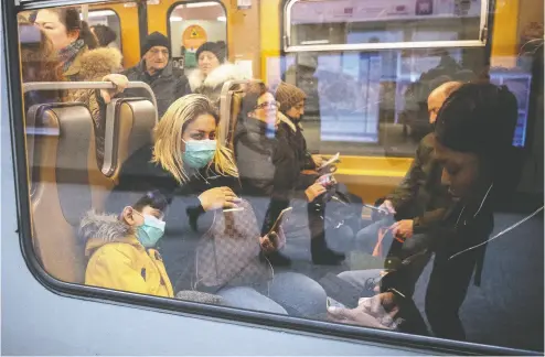  ?? Leon Neal / Gett
y Imag
es ?? A woman and a small child wear protective masks as they travel on the undergroun­d train system in Belgium on
Tuesday. The European Parliament has announced that it will limit access to visitors for three weeks.