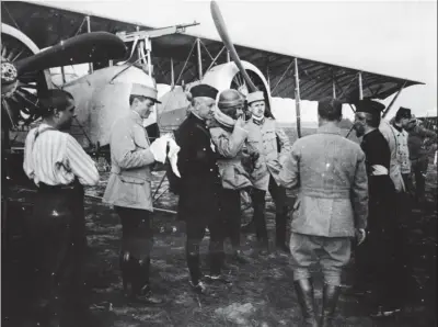  ?? SHD ?? Le cne Henri de Kérillis (mains dans les poches) avec ses hommes, devant un Caudron G.4 armé d’une mitrailleu­se Colt. L’homme en soutane à droite est probableme­nt le s/lt Léopold Mirabail, observateu­r et prêtre dans la vie civile.