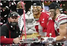  ?? JOHN BAZEMORE — THE ASSOCIATED PRESS ?? From left, Ohio State coach Ryan Day, quarterbac­k Justin Fields and linebacker Tuf Borland hold up the trophy after the Buckeyes beat Clemson in a College Football Playoff semifinal Friday. Ohio State can win its first national title since 2014 by beating Alabama on Monday.