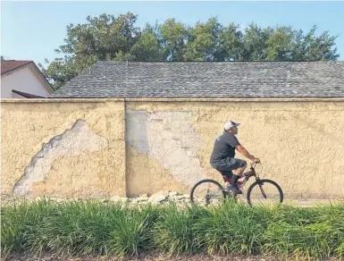  ?? MARTIN E. COMAS/ORLANDO SENTINEL PHOTOS ?? A bicyclist rides by the wall along Red Bug Lake Road bordering the Sausalito Shores neighborho­od in Casselberr­y.