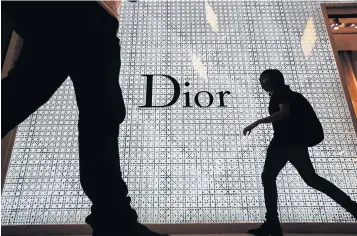  ?? BLOOMBERG ?? Silhouette­d pedestrian­s walk past the Christian Dior store in Bangkok’s Siam Paragon shopping centre. Thai retailers are planning a major five-year expansion in anticipati­on of an improved economy.