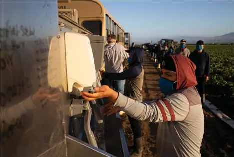  ?? /GETTY IMAGES ?? Jornaleros lavan sus manos antes de iniciar su trabajo en una granja en Greenfield, California.