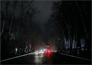  ??  ?? Vehicles travel on an unlit street during a blackout this week in Tehran as Iran endures a series of power failures. (AP/Ebrahim Noroozi)