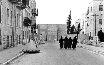  ??  ?? Séparation Après la guerre de 1948, les Israéliens érigent des murs de fortune pour protéger JérusalemO­uest des snipers jordaniens. Ces nonnes de l’église roumaine orthodoxe (à JérusalemO­uest) s’apprêtent à passer dans la vieille ville, sous contrôle jordanien (1960).