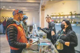  ?? NATHAN BURTON/Taos News ?? Southwest Cannabis employee Sheree Duran, right, helps customer Hugo Billard of Taos Ski Valley on April 1, the opening day for recreation­al cannabis sales in New Mexico.