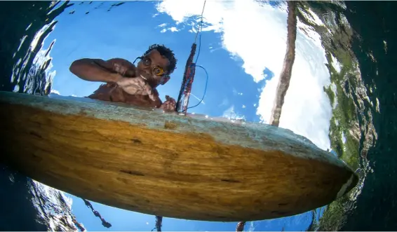  ??  ?? ABOVE One of Raja's fishermen, wearing home-made goggles, peers through the water RIGHT PAGE A pulsing school under Arborek’s jetty – evidence of a thriving ecosystem