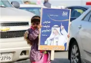  ??  ?? A child holds up a candidate’s poster outside a polling station yesterday.—Photos by Yasser Al-Zayyat