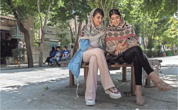  ?? PHOTOS BY FARHAD BABAEI/SPECIAL TO USA TODAY ?? Kimia Naderzadeh, right, and her cousin, Maryam Dehnavi, sit in the shade on a pedestrian street in Isfahan.