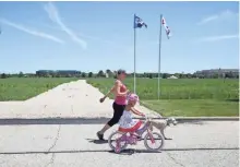  ?? MICHAEL SEARS / MILWAUKEE JOURNAL SENTINEL ?? Erica Nuss of the Town of Oconomowoc and her daughter Brooke, 4, and dog Lucy walk past a temporary gravel road at Pabst Farms, where a field will provide parking for the U.S Open.