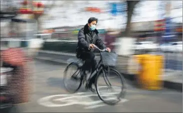  ??  ?? TIME TO ESCAPE? A man wearing a face mask rides a bicycle in Beijing.
REUTERS