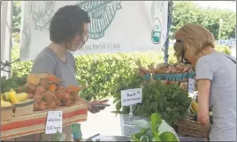  ?? STAFF PHOTOS BY MICHAEL SYKES II ?? Jennifer Paulk shows a customer how much her produce will cost at the Sassafras Creek farm stand in the BAE parking lot in Lexington Park.