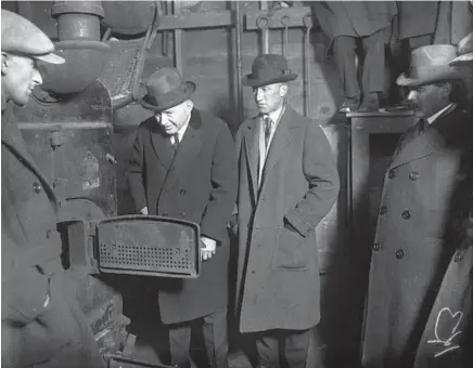  ?? CHICAGO HERALD AND EXAMINER ?? The greenhouse furnace where Warren Lincoln, third from left, burned the headless bodies of his wife Lina Lincoln and her brother Byron Shoup in Aurora in 1924. Aurora police Chief Frank Michels is second from left.