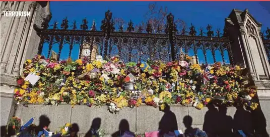  ?? AFP PIC ?? The shadows of onlookers are cast on floral tributes to the victims of the March 22 terror attack in central London on Saturday.