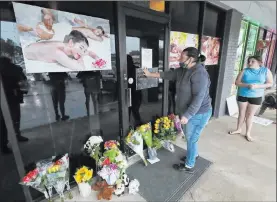  ?? Curtis Compton The Associated Press ?? Jessica Lang places her hand on the door in a moment of grief Wednesday after dropping off flowers with her daughter Summer at Youngs Asian Massage parlor, where four people were killed, in Acworth, Ga.