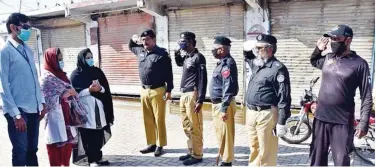  ??  ?? ↑ Police officers salute doctors for treating coronaviru­s patients in a hospital in Larkana, Sindh province.