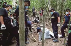  ?? FILE PIC ?? A forensics team digging up the remains of a human traffickin­g victim in Bukit Wang Burma, Padang Besar, in May 2015.