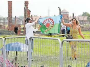  ?? FOTO: CZAREK SOKOLOWSKI/AP/DPA ?? Zwei Besucher des ehemaligen Vernichtun­gslagers Auschwitz-Birkenau halten in Gedenken an die ermordeten Sinti und Roma eine Roma-Fahne. Noch immer muss Europas größte Minderheit um Gleichbere­chtigung kämpfen. Im Saarland droht diesbezügl­ich jetzt ein großer Rückschlag.