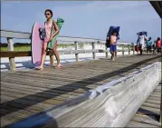  ?? MEL EVANS / AP ?? People stream onto the beach Tuesday at Island Beach State Park in Seaside Park, N.J., after a budget impasse between the Republican governor and Democratic lawmakers shut down the government.