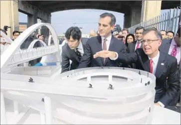  ?? Irfan Khan Los Angeles Times ?? L.A. CITY ENGINEER Gary Moore, right, Mayor Eric Garcetti and others look at a model of the new viaduct. Meeting the city’s budget of approximat­ely $200 million for design and constructi­on has been a challenge.