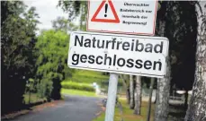  ?? FOTOS: DPA ?? Vor dem Sennfelder Badesee ist ein Schild aufgehängt, das auf die Schließung des Sees hinweist.