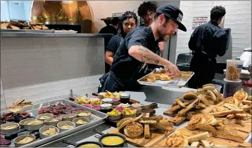  ?? PHOTOS BY GRETCHEN MCKAY — PITTSBURGH POST-GAZETTE ?? Cafe Momentum chef de cuisine Peter Henry plates biscuits for a soft opening dinner on Feb. 6at the soon-to-open restaurant on Forbes Avenue in downtown Pittsburgh.