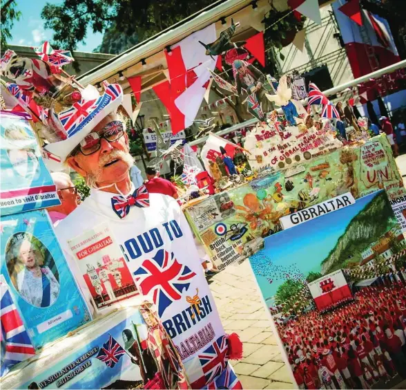  ?? EFE ?? Un gibraltare­ño porta carteles y banderas de Reino Unido que reclaman la visita de la Reina Isabel II al Peñón