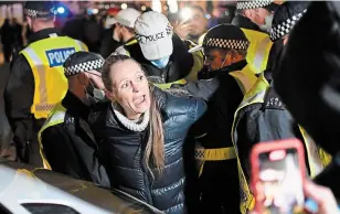  ?? ALBERTO PEZZALI THE ASSOCIATED PRESS ?? A woman is detained by police during “The Million Mask March” in central London on Thursday. The march was taking place on the same day national lockdown rules come into force in Britain.